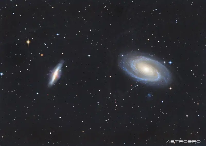 Galaxies M81 et M82 photographiées au télescope : à droite la spirale de Bode aux bras bleutés autour d'un noyau doré, à gauche la galaxie du Cigare vue par la tranche avec ses jets de matière rougeâtres.