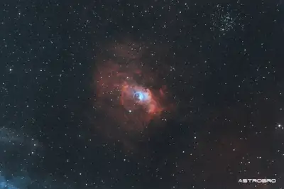 Nébuleuse de la Bulle (NGC 7635) photographiée au télescope : sphère de gaz presque parfaite se détachant sur un fond d'hydrogène rouge, avec l'étoile responsable décalée du centre, dans Cassiopée.