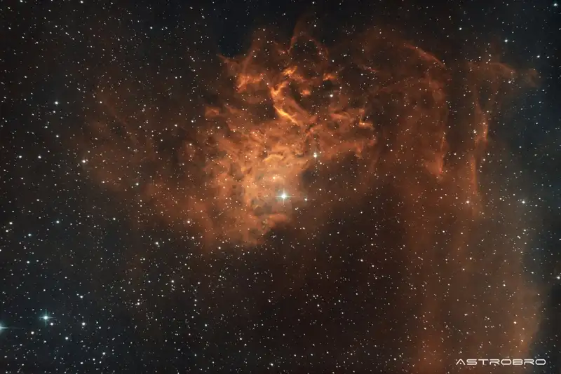 Nébuleuse de l'Étoile Flamboyante (IC 405) photographiée au télescope : volutes de gaz orange et cuivré striées de filaments sombres, autour de l'étoile brillante AE Aurigae, sur un champ dense d'étoiles.