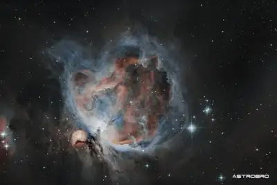 Nébuleuse d'Orion (M42) photographiée au télescope : vaste nuage de gaz bleu et rose entourant l'amas du Trapèze, avec la nébuleuse de l'Homme qui court en bas à gauche, sur fond d'étoiles.