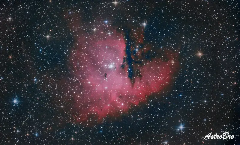 Nébuleuse Pacman (NGC 281) photographiée au télescope : nuage d'hydrogène rouge échancré par une bande de poussière sombre lui donnant une silhouette de bouche ouverte, dans Cassiopée.