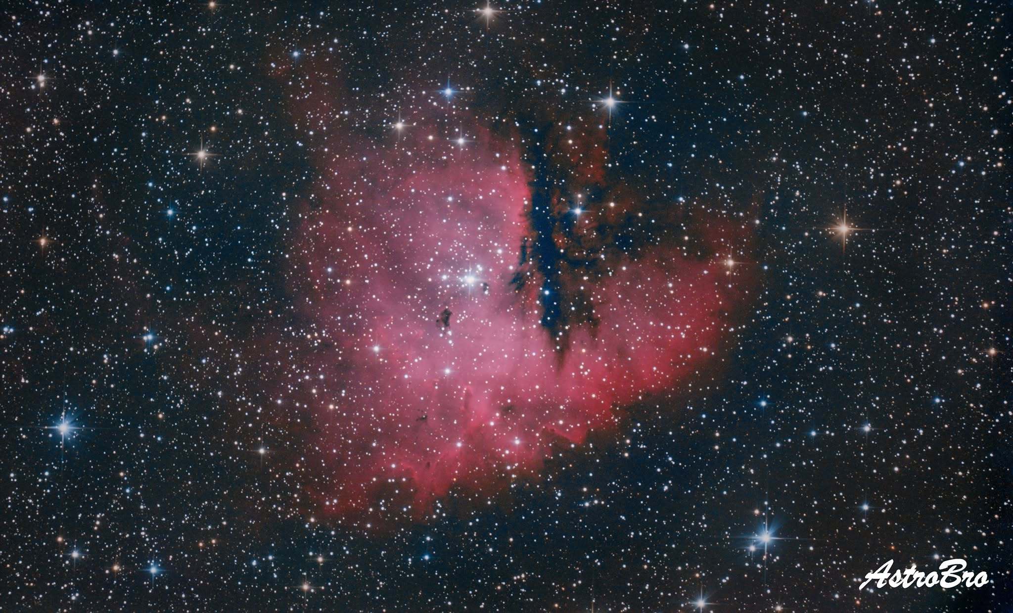 Nébuleuse Pacman (NGC 281) photographiée au télescope : nuage d'hydrogène rouge échancré par une bande de poussière sombre lui donnant une silhouette de bouche ouverte, dans Cassiopée.