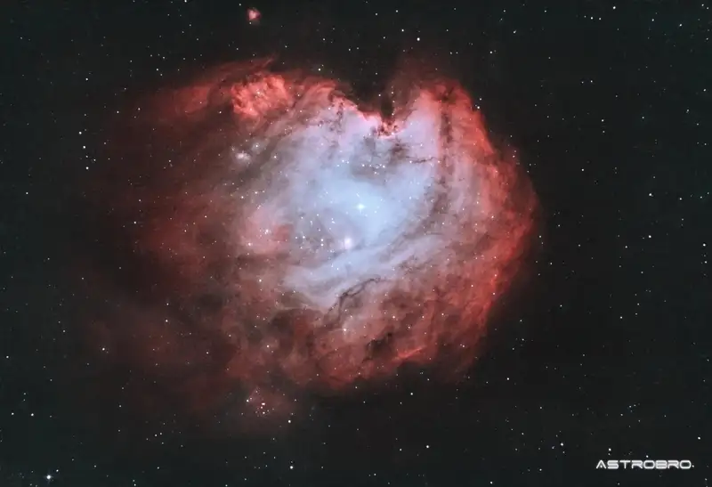 Nébuleuse de la Tête de Singe (NGC 2174) photographiée au télescope : nuage d'hydrogène rouge dont les volutes et les colonnes de poussière dessinent un profil de primate, dans la constellation d'Orion.